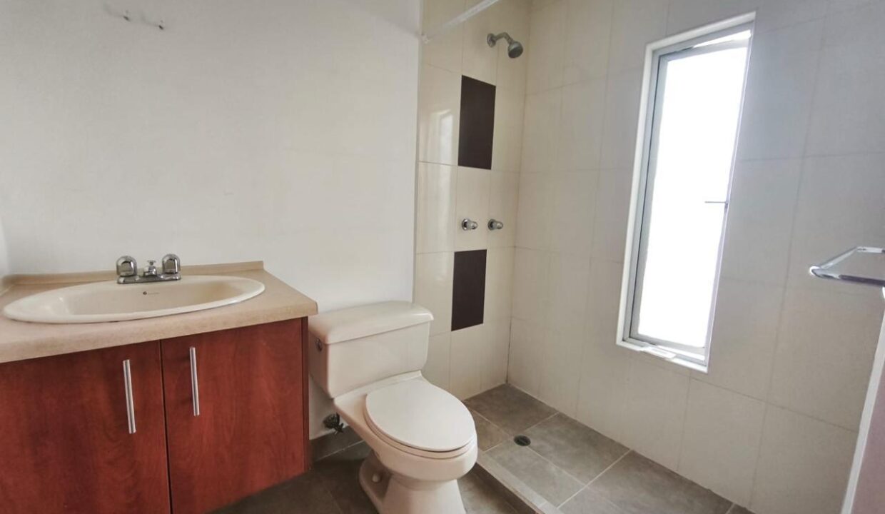 Baño completo con ducha, mesón y ventana en casa en Pomasqui, Quito