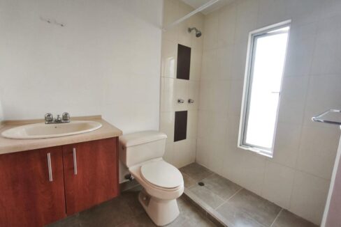Baño completo con ducha, mesón y ventana en casa en Pomasqui, Quito