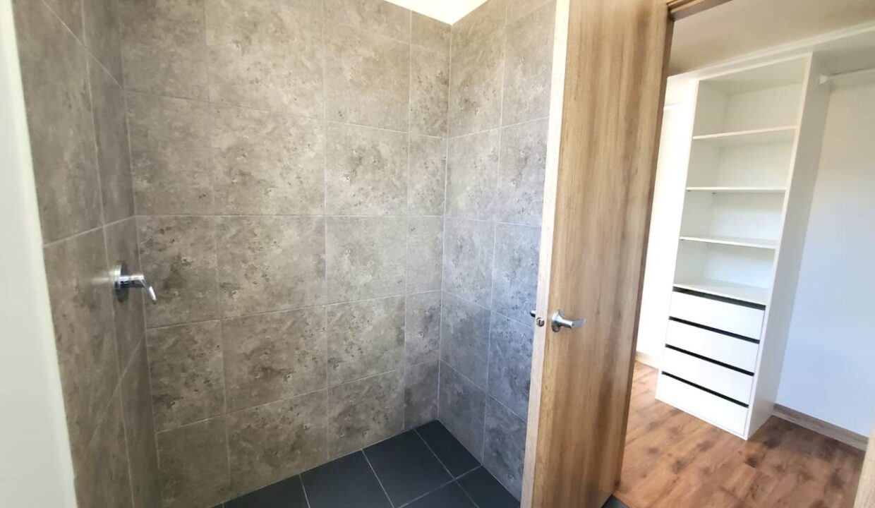 Baño completo con ducha y walking closet del dormitorio máster en Pomasqui, Quito