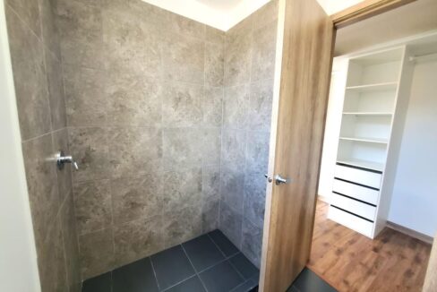 Baño completo con ducha y walking closet del dormitorio máster en Pomasqui, Quito