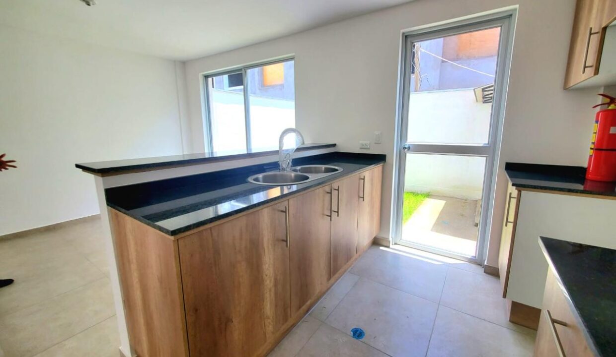 Cocina con mesón de granito y fregadero de dos pozos en Pomasqui, Quito