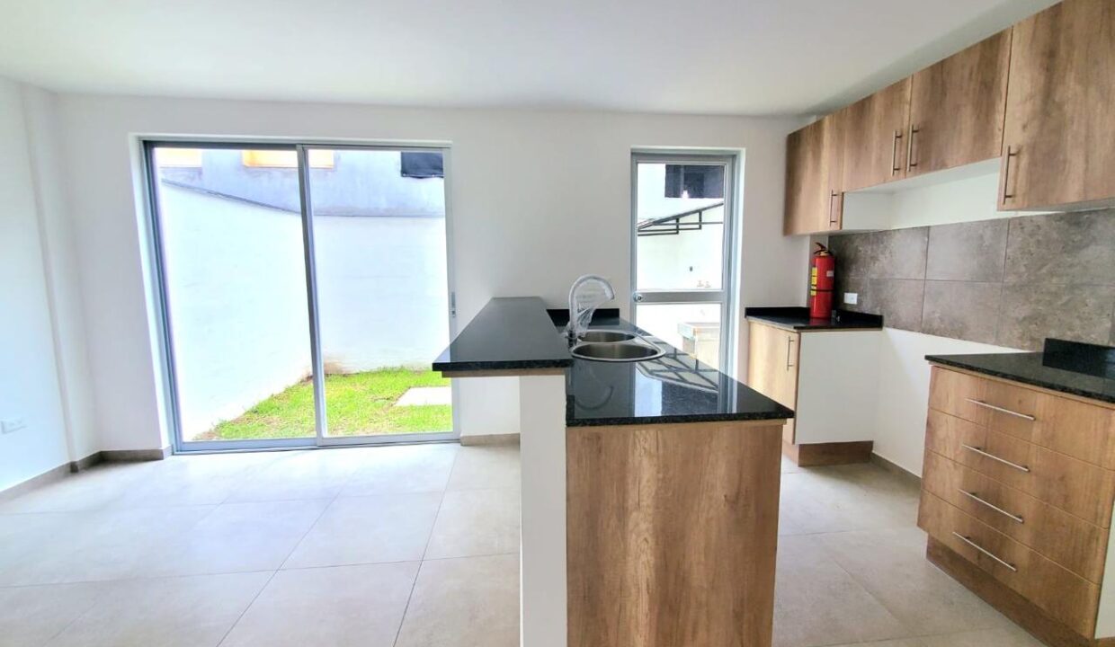 Cocina abierta con muebles altos y bajos y mesón de granito en Pomasqui, Quito