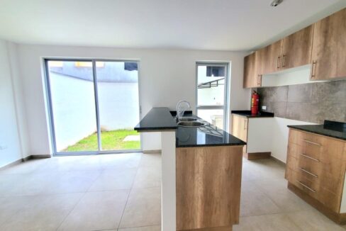 Cocina abierta con muebles altos y bajos y mesón de granito en Pomasqui, Quito