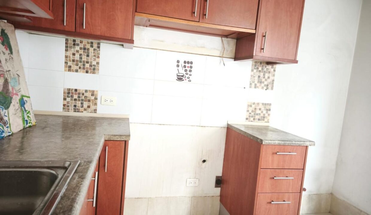 Cocina con muebles de madera y cenefa de mosaico en casa en venta en Pomasqui, Quito