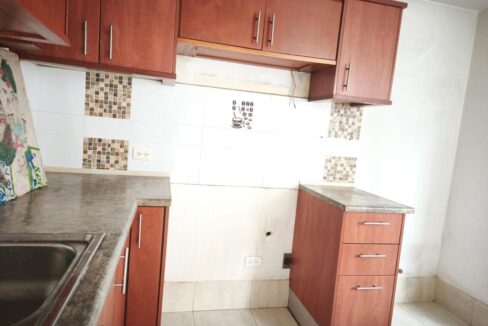 Cocina con muebles de madera y cenefa de mosaico en casa en venta en Pomasqui, Quito