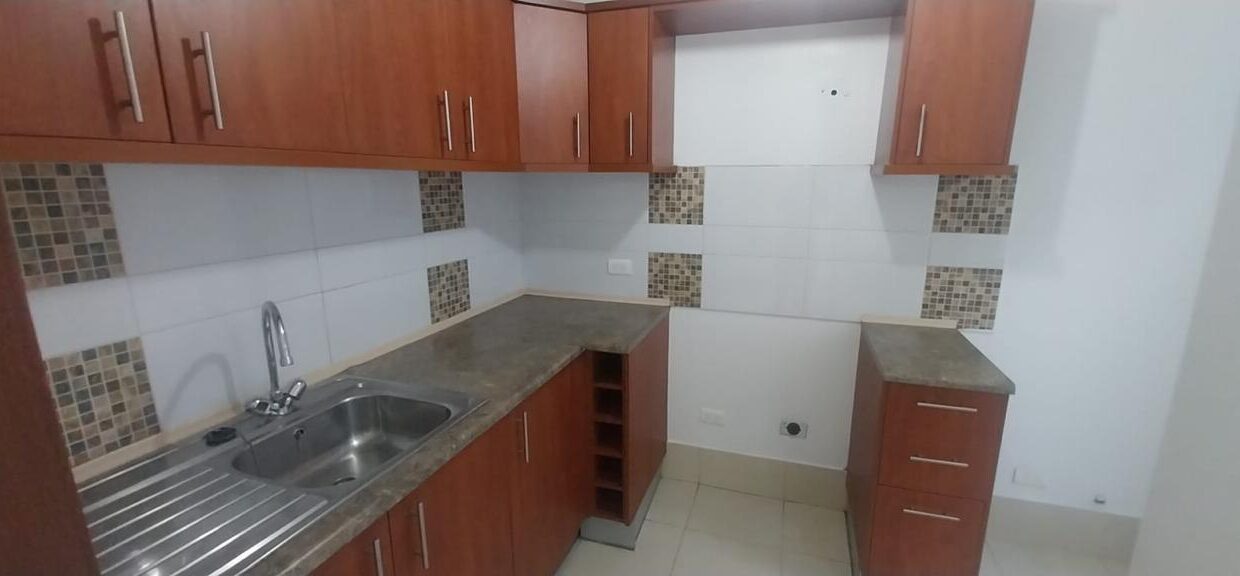 Cocina semi abierta con muebles altos y bajos y mesón en casa en Pomasqui, Quito