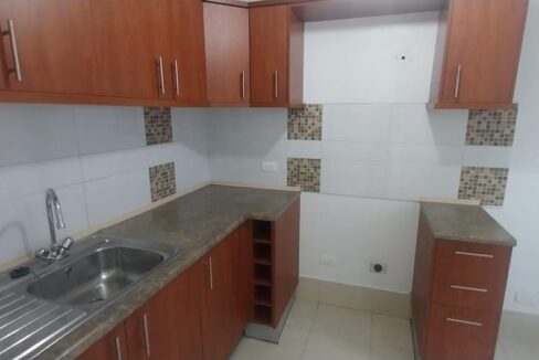 Cocina semi abierta con muebles altos y bajos y mesón en casa en Pomasqui, Quito