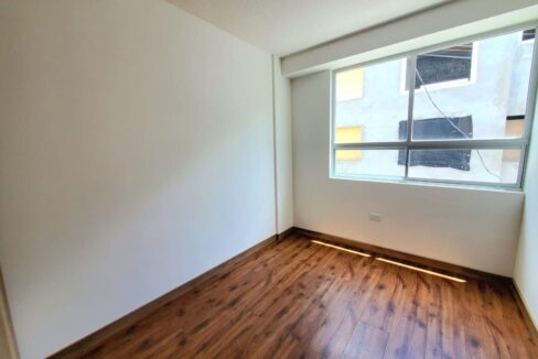 Dormitorio con piso flotante y ventanal en casa en venta en Pomasqui, norte de Quito