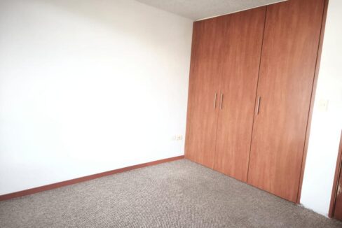 Dormitorio con amplio closet de madera en casa en venta en Pomasqui, Quito