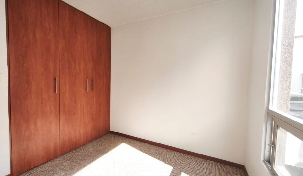 Dormitorio con closet de madera y ventanal en casa en Pomasqui, norte de Quito
