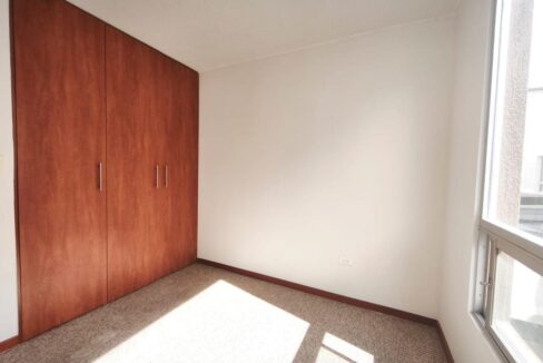 Dormitorio con closet de madera y ventanal en casa en Pomasqui, norte de Quito
