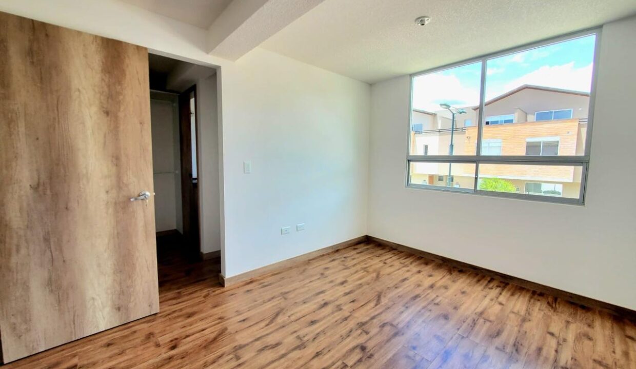 Dormitorio máster con walking closet y ventanal amplio en Pomasqui, Quito