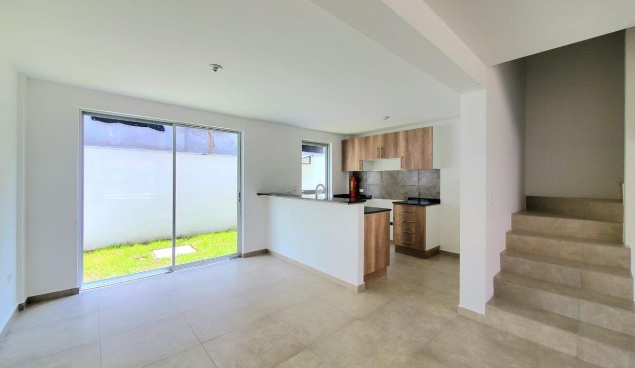 Sala comedor con cocina abierta y gradas en casa en venta en Pomasqui, Quito