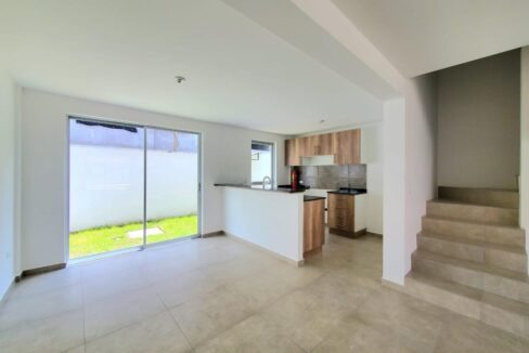 Sala comedor con cocina abierta y gradas en casa en venta en Pomasqui, Quito